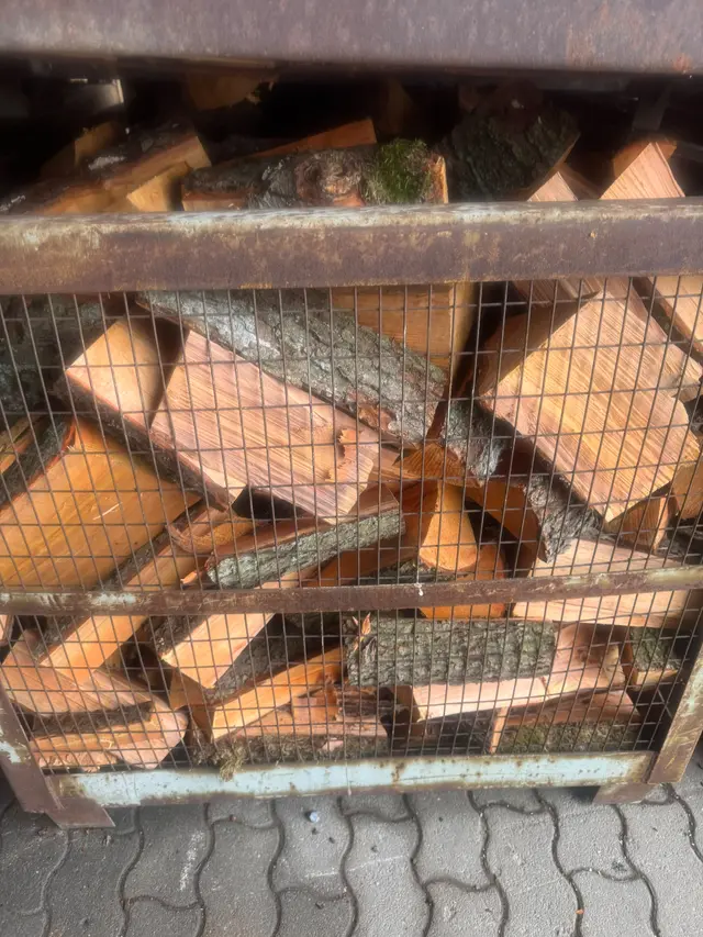 Halb geöffnete Gitterbox mit sortiertem Scheitholz